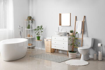 Interior of light bathroom with drawers, toilet bowl and laundry basket