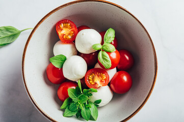 Classic italian salad caprese served in original form with cherry tomatoes, mini mozarella pearls and basil