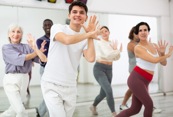 Emotional young guy enjoying active dancing during group training in dance studio..