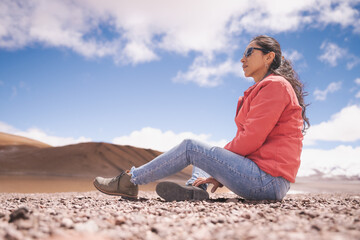 Fototapeta na wymiar mujer latina contemplando laguna entre montañas nevadas de los Andes