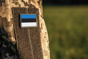 Close up millitary woman or man shoulder arm sleeve with Estonia flag patch. Estonia troops army, soldier camouflage uniform. Armed Forces, empty copy space for text

