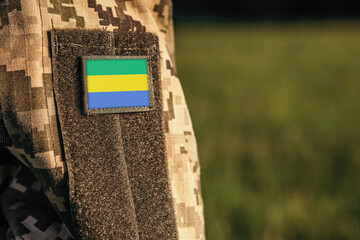 Close up millitary woman or man shoulder arm sleeve with Gabon flag patch. Gabon troops army, soldier camouflage uniform. Armed Forces, empty copy space for text


