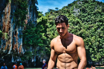 Half body shot of a handsome young man standing on a beach in Phuket Island, Thailand