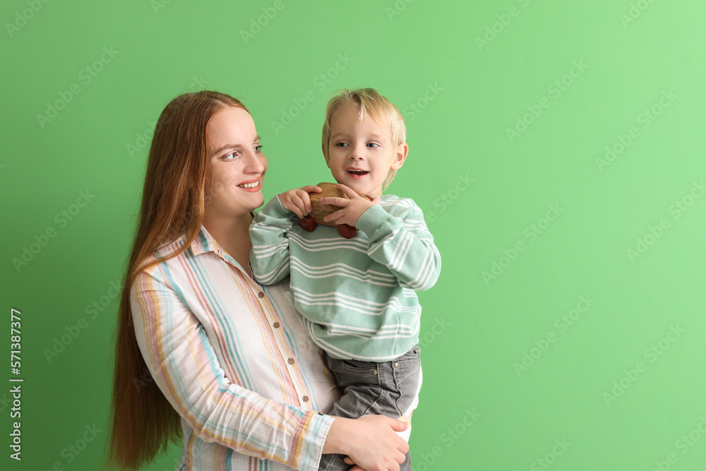 Wall mural happy mother and her little son with toy car on green background