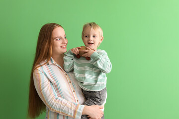 Happy mother and her little son with toy car on green background