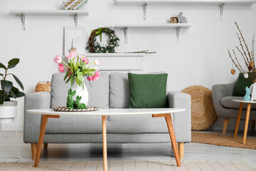 Vase with tulips and Easter rabbits on table in interior of living room