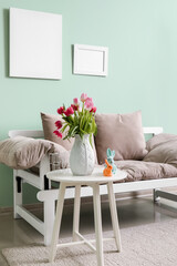 Vase with tulips and Easter bunnies on end table in living room