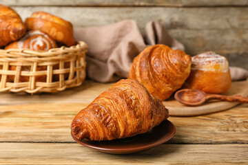 Plate with delicious croissant on wooden table