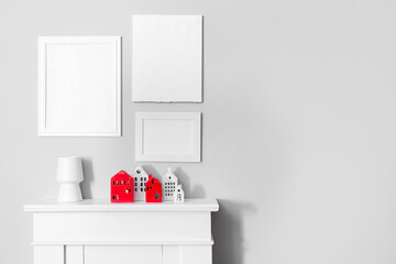 Interior of room with house candle holders on fireplace and blank frames near grey wall