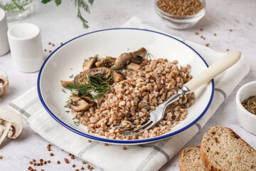 Plate of tasty buckwheat porridge with mushrooms and dill on grey table