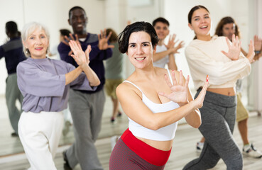 Happy young Latina enjoying active dancing during group training in dance studio..