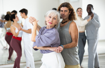 Caucasian man and mature woman rehearsing latin paired dance moves