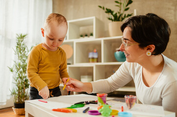 Fototapeta premium Mother and son drawing with crayons at home and having education