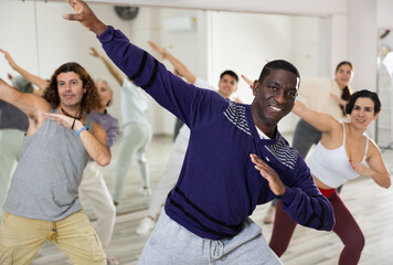 Group of adult people, engaged in the dance school, practices dance aerobics in class