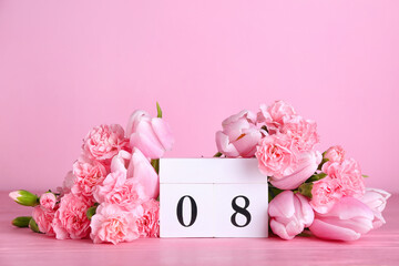 Cube calendar with date MARCH 8 and beautiful flowers on pink table. Women's Day celebration