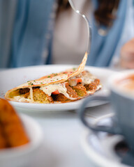 a person opening a falafel tortilla on a plate with a fork and knife