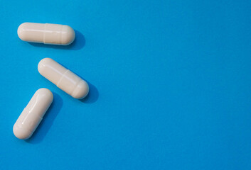 Close up three white Pills of Medicine over blue background with copy space, top view.