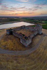 Aerial view of Valongo castle, Evora, Alentejo, Portugal with a lagoon and vineyards at sunset