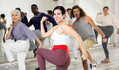 Active people of different nationalities learn sports dancing at a group class in a dance studio