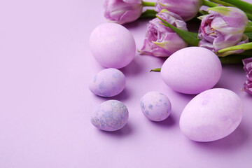 Fototapeta na wymiar Easter eggs and beautiful tulip flowers on lilac background, closeup