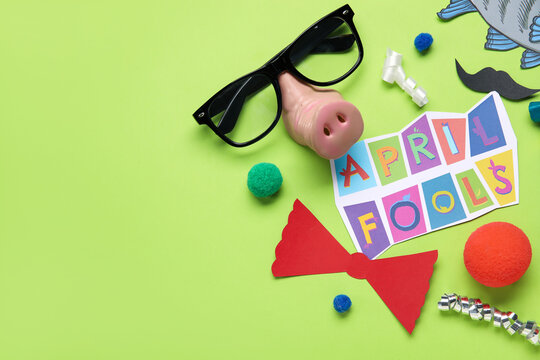 Composition with text APRIL FOOLS and party decor on green background