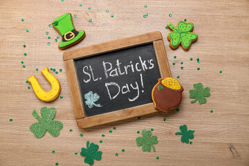 Chalkboard with text ST. PATRICK'S DAY, cookies and decor on wooden background