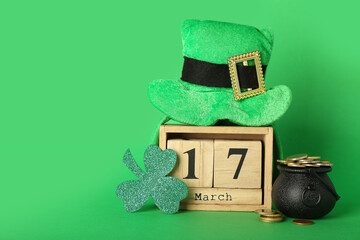 Calendar with date of St. Patrick's Day, paper clover, Leprechaun hat and coins on green background