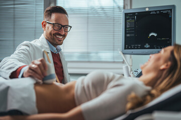 Mid adult male doctor using ultrasound scanner. Ultrasound exam. Doctor's hands on a woman's...