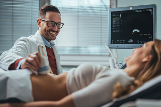 Mid adult male doctor using ultrasound scanner. Ultrasound exam. Doctor's hands on a woman's stomach, ultrasound of the abdominal cavity, close-up. Diagnosis of diseases of the genitourinary system