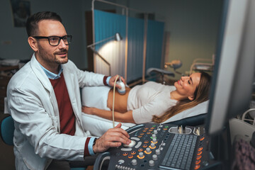 Selective focus on ultrasound scanner device in the hand of a professional doctor examining his patient doing abdominal ultrasound scanning sonogram sonography sonographer early pregnancy