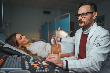 Gynecologist doctor does ultrasound, sonogram procedure to a pregnant woman. Doctor makes the patient women abdominal ultrasound. Ultrasound Scanner in the hands of a doctor. Diagnostics. Sonography