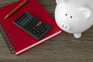 Calculator, pen and red notebook with piggy bank on table. Financial concept. 