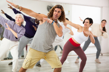 Group of adult people, engaged in the dance school, practices dance aerobics in class