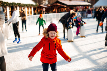 A young girl is skating on an outdoor rink. Girl in a red jacket. happy childhood