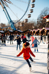 Obraz premium A young girl is skating on an outdoor rink. Girl in a red jacket. happy childhood