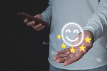 Evaluation and satisfaction concept. In smartphone application, a person chooses a smile emotion with five star. That is an excellent review. Medium close up shot with virtual screen.
