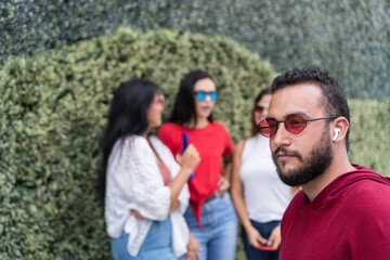 A young man with sunglasses looking away near friends