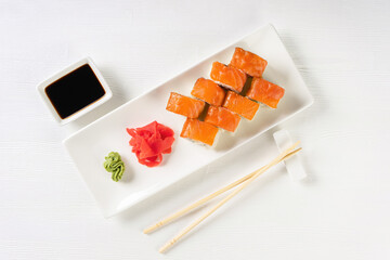 Sushi roll Philadelphia with salmon, smoked eel, avocado, cream cheese on white background. Sushi menu, rolls served on white dish with wasabi, ginger and soy sauce. Japanese cuisine food.
