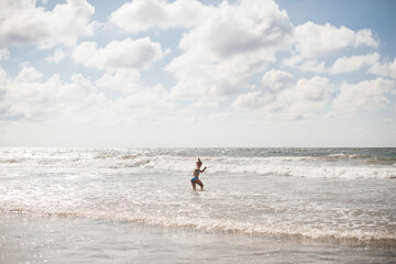 Fototapeta na wymiar Little girl play along the beach by the sea. 