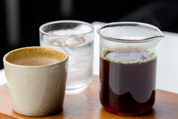 Coffee cup, and drip coffee jar, placed on a table wooden.