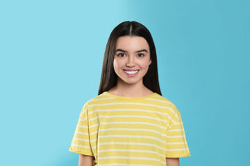 Portrait of happy teenage girl on light blue background