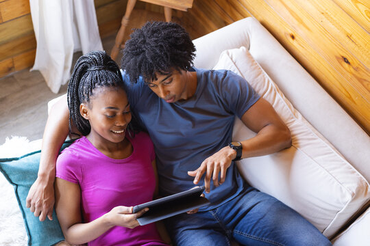 Happy african american couple spending time in log cabin using tablet