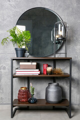 Stylish round mirror, lamp and houseplant on stand indoors. Interior design