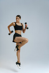 Fototapeta na wymiar Woman doing cardio exercises with dumbbells on studio background . Healthy lifestyle