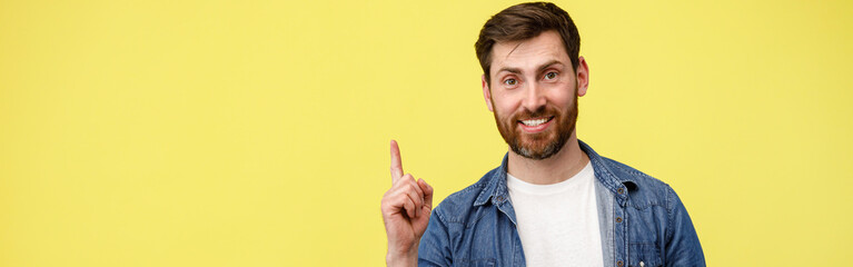 Obraz premium Smiling man raised finger up as sign he has new idea on yellow studio background