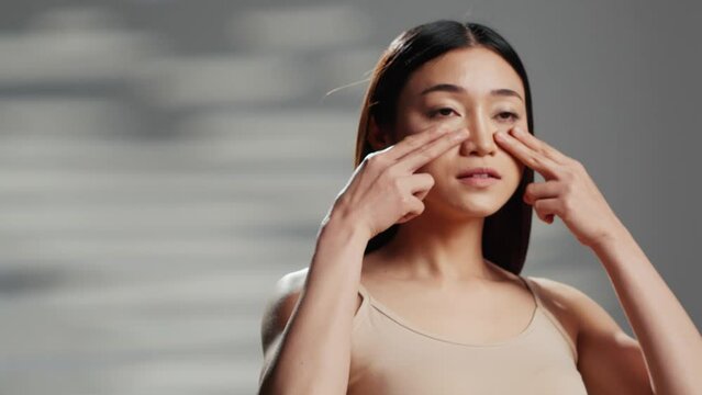 Beautiful girl using moisturizer or serum for beauty routine, applying face cream on cheecks and promoting natural cosmetics or products. Sensual woman with glowing skin, self love.