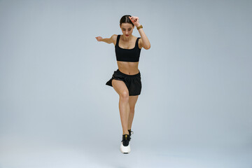 Athletic active woman wearing sportswear jumping on studio background. Dynamic movement