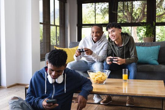 Image of happy diverse male teenage friends playing video games at home