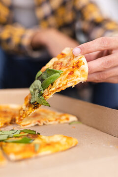 Vertical image of hands of biracial teenager boy with pizza slice
