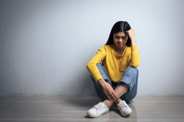 Teenage Asian girl with depression sitting alone in white room. Sad woman sitting alone in empty...